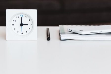 Books On Time Management | BookSummaryClub white desk clock near pen and book