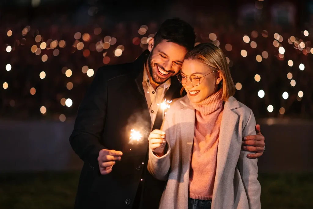 How to Keep New Year’s Resolutions and Improve Your Relationship Happy couple celebrating New Year’s Eve with sparklers, symbolizing keeping New Year’s resolutions for stronger relationships through shared goals and quality time.