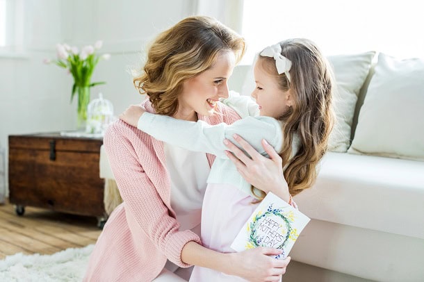 145 Inspirational Mother’s Day Quotes to Help You Express Your Love and Gratitude A mother embracing her smiling young daughter whole holding a Mother